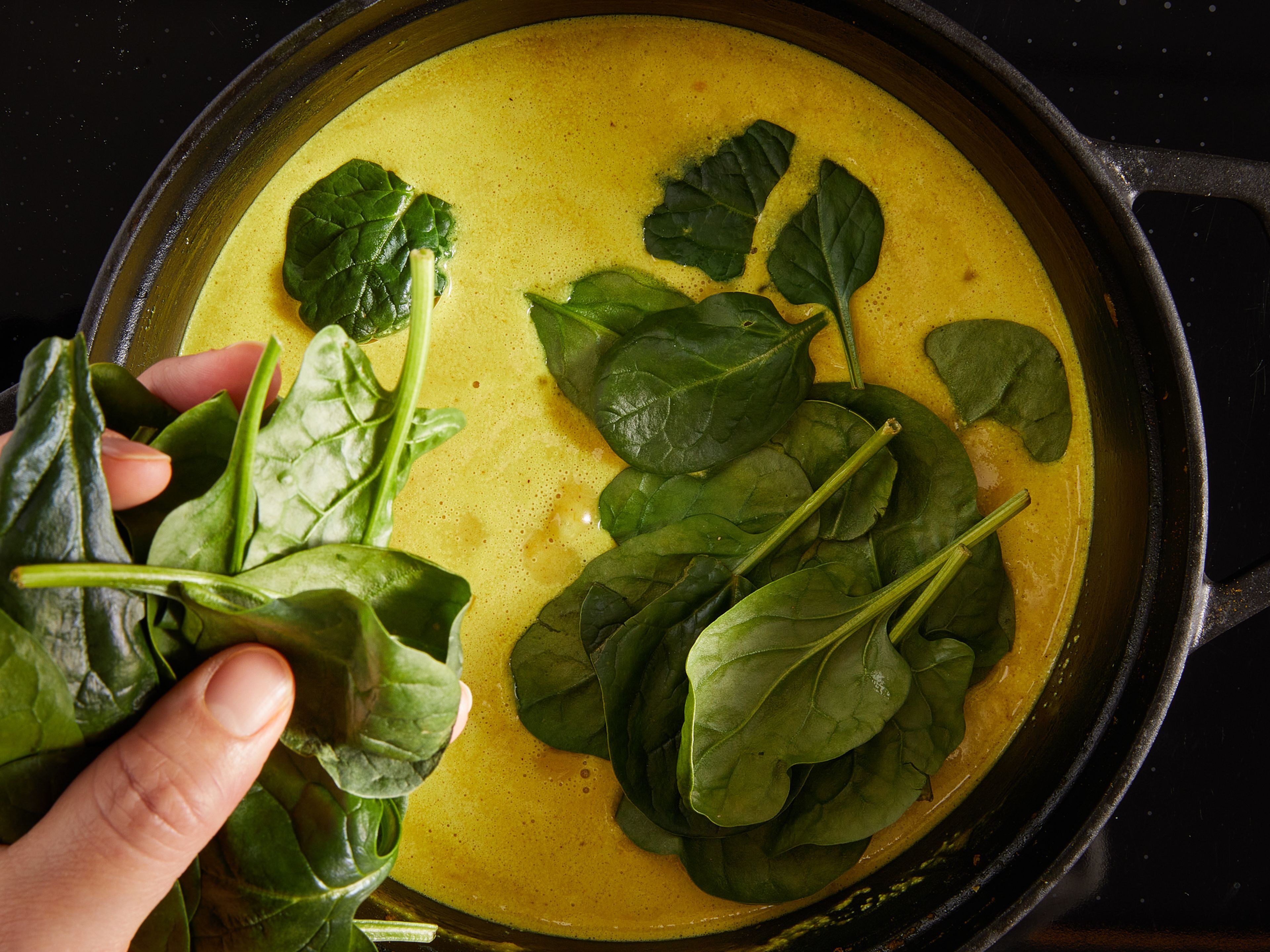 Add water and scrape the bottom of the pot. Bring to a boil, letting it cook on a high simmer for approx. 5 min. Next, add coconut milk, season with salt and a pinch of sugar. Then reduce heat to medium, and cook, with the lid half on, for approx. 10 min. At the end of this cooking time, add lemon zest, and then juice, to taste. Turn off the heat, add the baby spinach and stir well. Then, place the lid on and leave the spinach to wilt for approx. 5 min. Serve with basmati rice, and extra green chili on top, if desired. Enjoy!