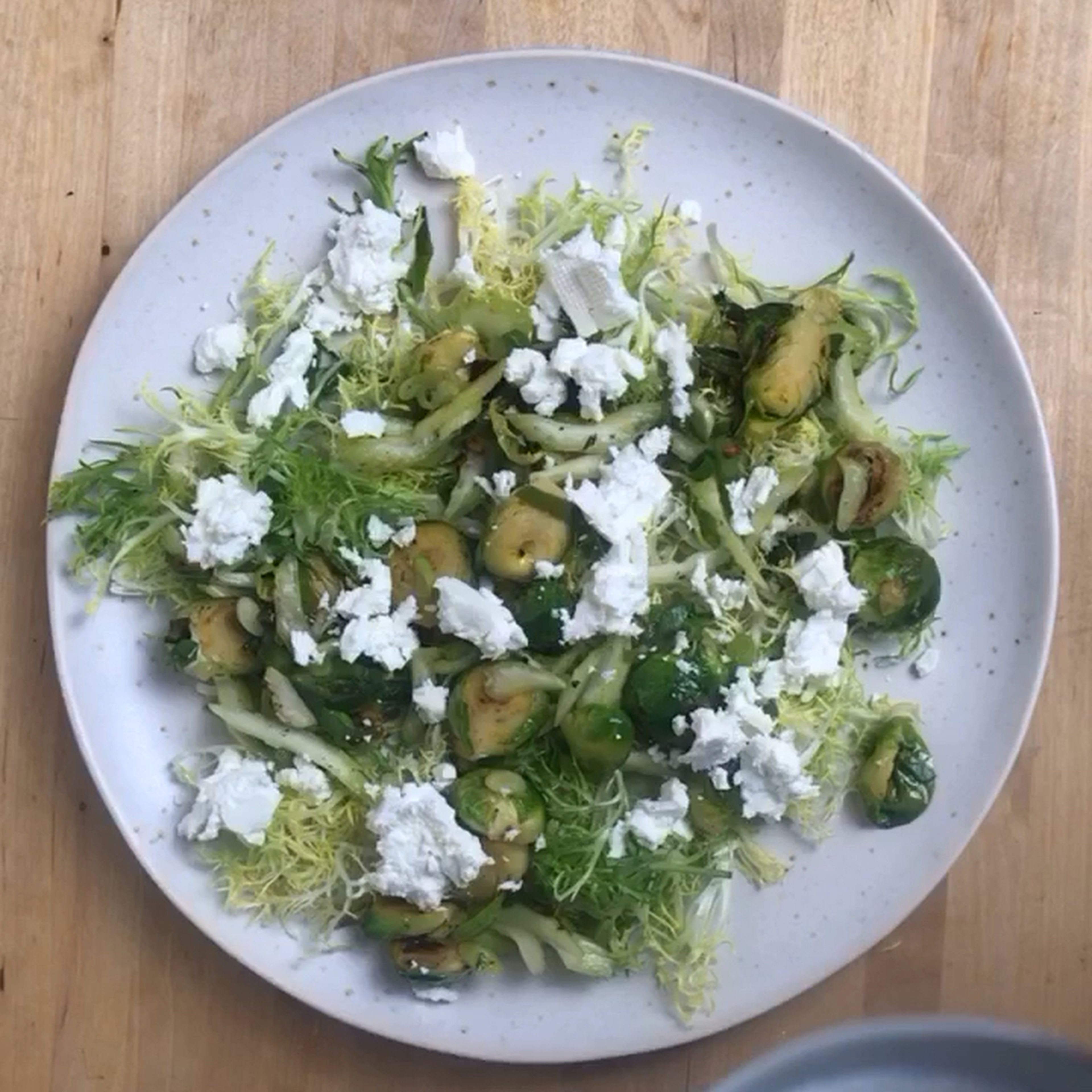 Now assemble the salad. First frisée, then the vegetables. Roughly crumble feta cheese over it and spread the yogurt on top. In the end, spread the pomegranate seeds and the coconut flakes on top.