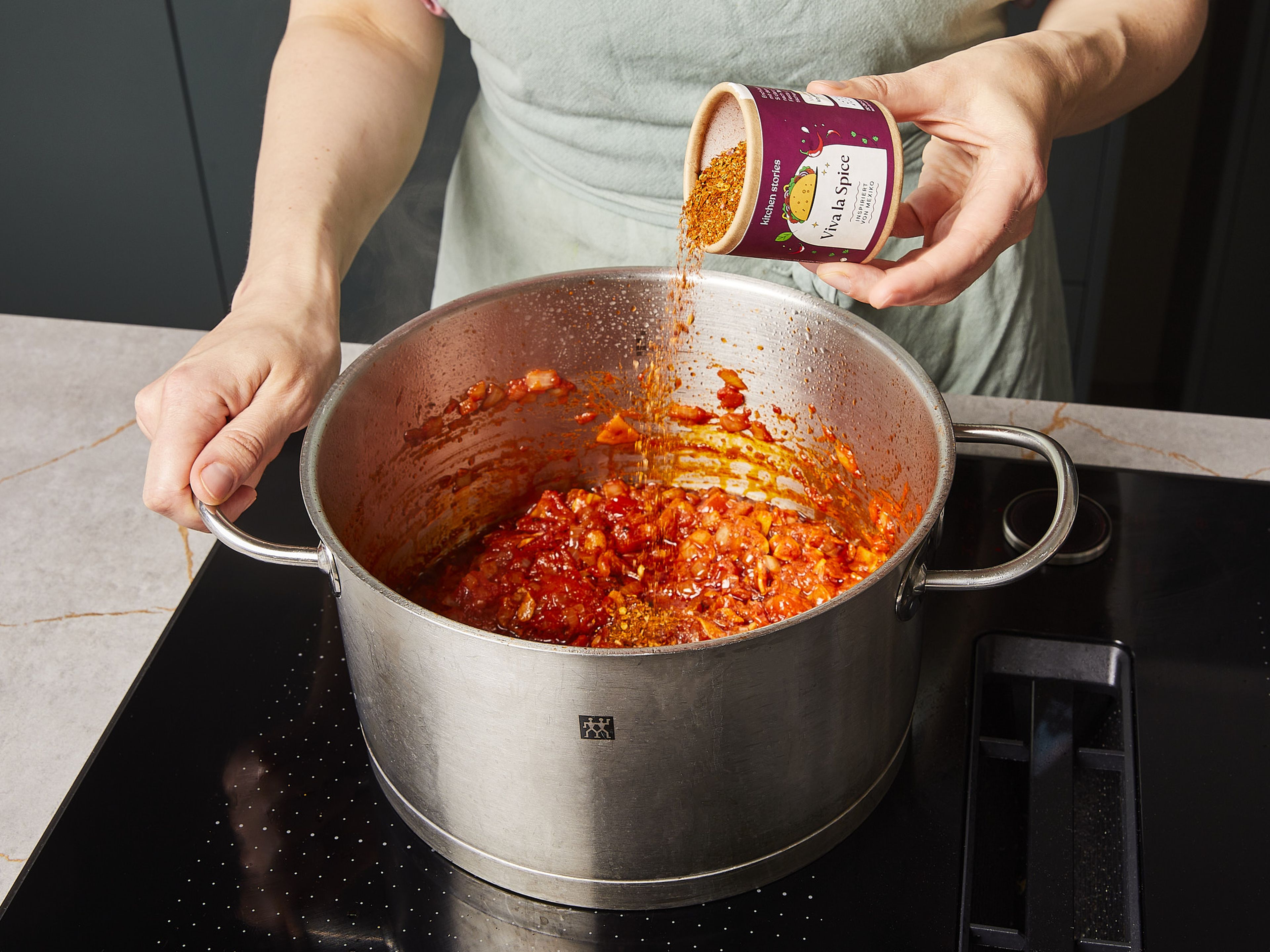 Tomaten und Knoblauch zugeben und ca. 2 Min. anbraten. Dann unsere VIVA LA SPICE Gewürzmischung und Rinderbrühe hinzufügen und verrühren. Hähnchenteile zurück in den Topf geben, zum Kochen bringen und bei mittlerer Hitze ca. 25–30 Min. köcheln lassen. In der Zwischenzeit den Koriander hacken. Limetten in Spalten schneiden.
