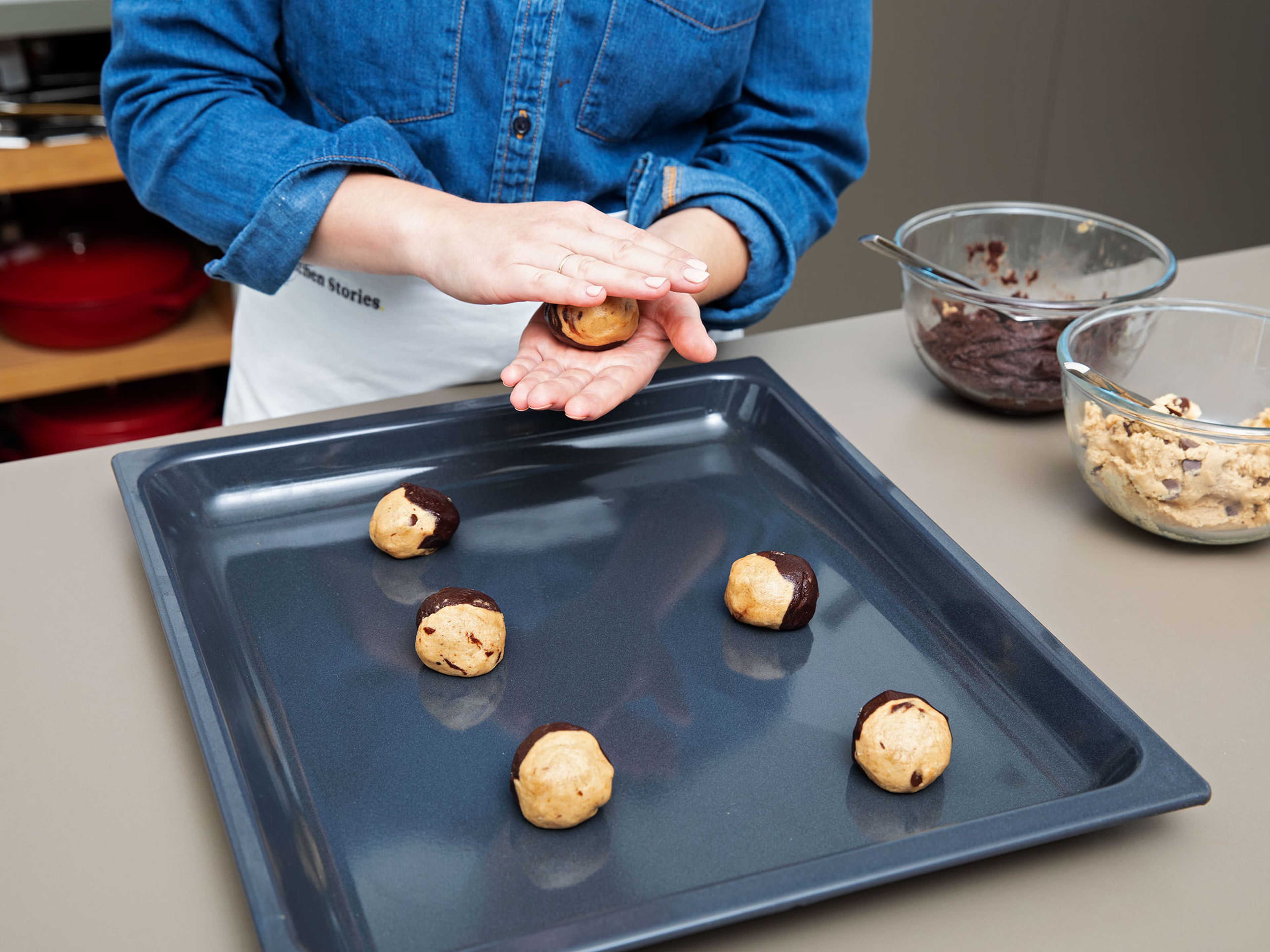 Backofen auf 175°C vorheizen. Falls nötig, ein Backblech mit Backpapier auslegen. Jeweils 1 Teelöffel vom Schokoladen- und Erdnussteig abmessen und beide zu einer Kugel rollen. Die beiden Teigkugeln zusammendrücken, zu einer großen Kugel formen und auf das Backblech legen. Etwas Abstand dazwischen lassen, weil die Kekse beim Backen aufgehen.