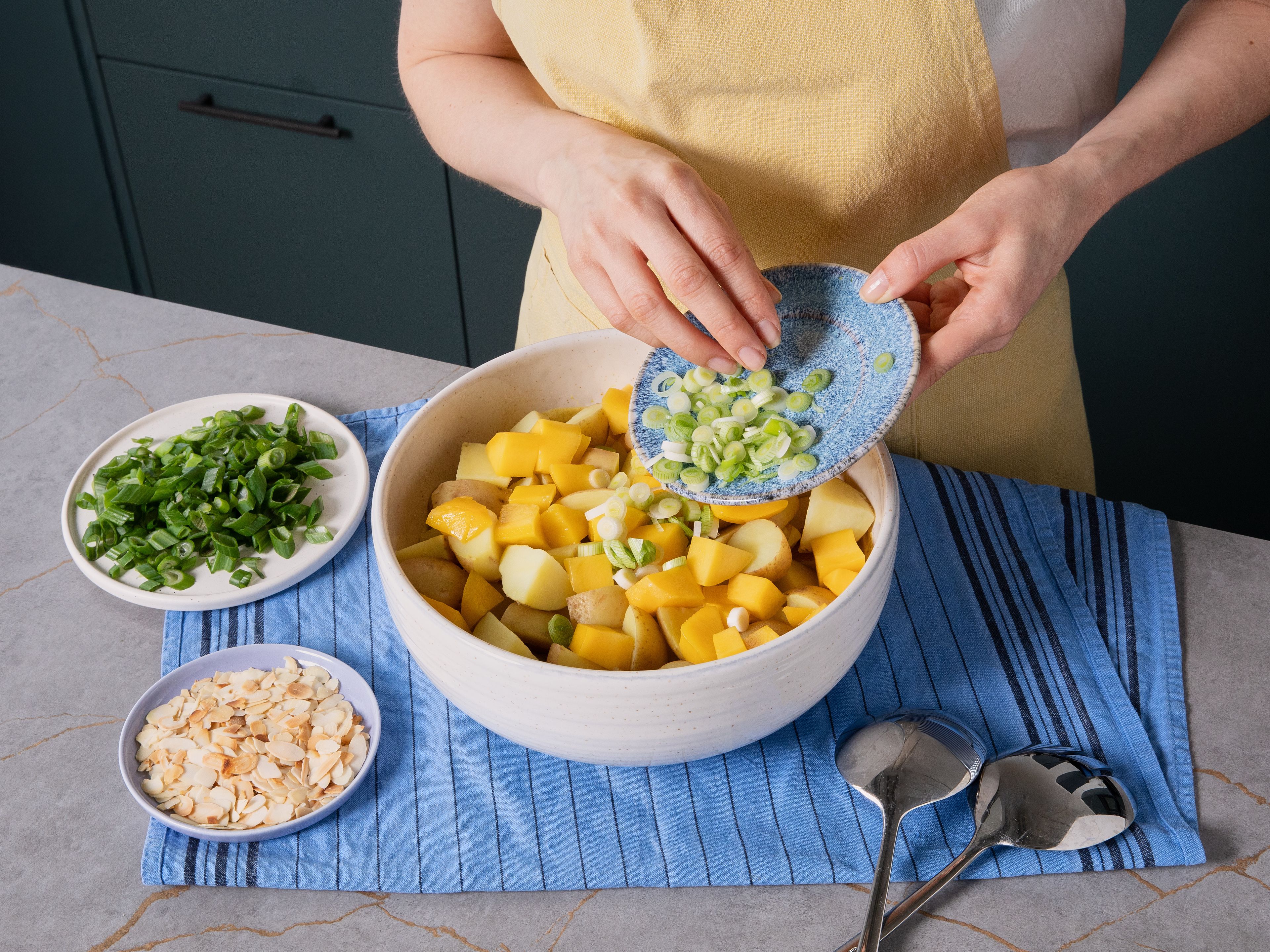 Add warm potatoes, mango, and white part of scallions to the dressing. Mix gently and let sit for approx. 10 min. To serve, sprinkle with toasted almond flakes, green part of scallions, and optionally garnish with lime juice, chili, and freshly cracked pepper. Serve warm or chilled.