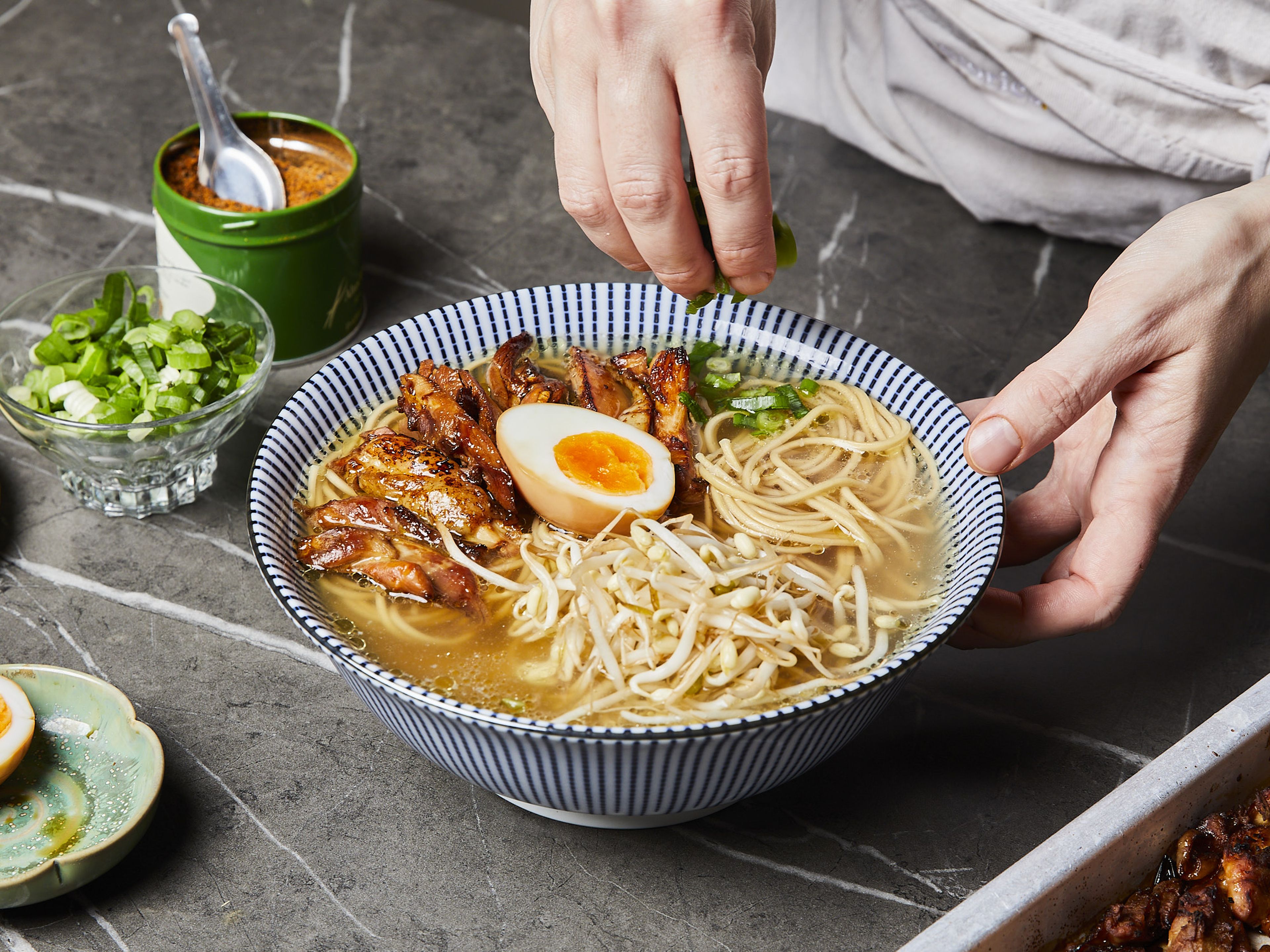 Cut scallion into thin rings. Remove the eggs from the marinade and cut each in half. Cook the ramen noodles according to package instructions. Pour the remaining seasoning sauce into serving bowls, place the cooked noodles on top and then fill up with stock. Then add chicken slices, half an egg, soy sprouts, dried seaweed, scallions and some shichimi togarashi, if desired.