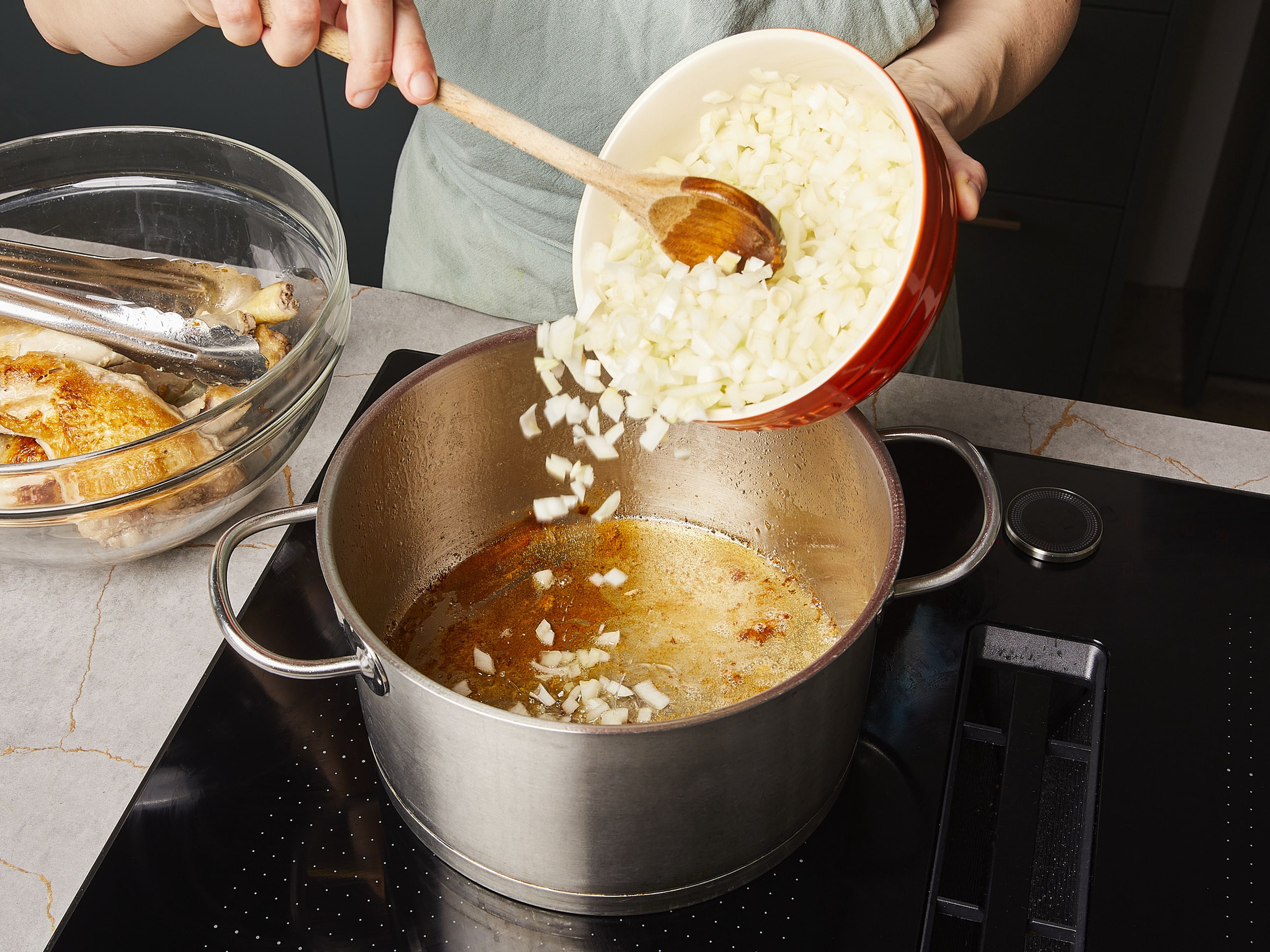 Zwiebeln fein würfeln. Tomaten würfeln. Knoblauch in Scheiben schneiden. Öl in einem großen Topf erhitzen und die Hähnchenschenkel von allen Seiten anbraten, dann aus dem Topf nehmen. Anschließend ¾ der Zwiebeln in den Topf geben, ca. 3–5 Min. anbraten und mit Salz würzen. Tomatenmark zugeben und weitere ca. 5-8 Min. braten, bis das Tomatenmark karamellisiert und dunkel geworden ist.