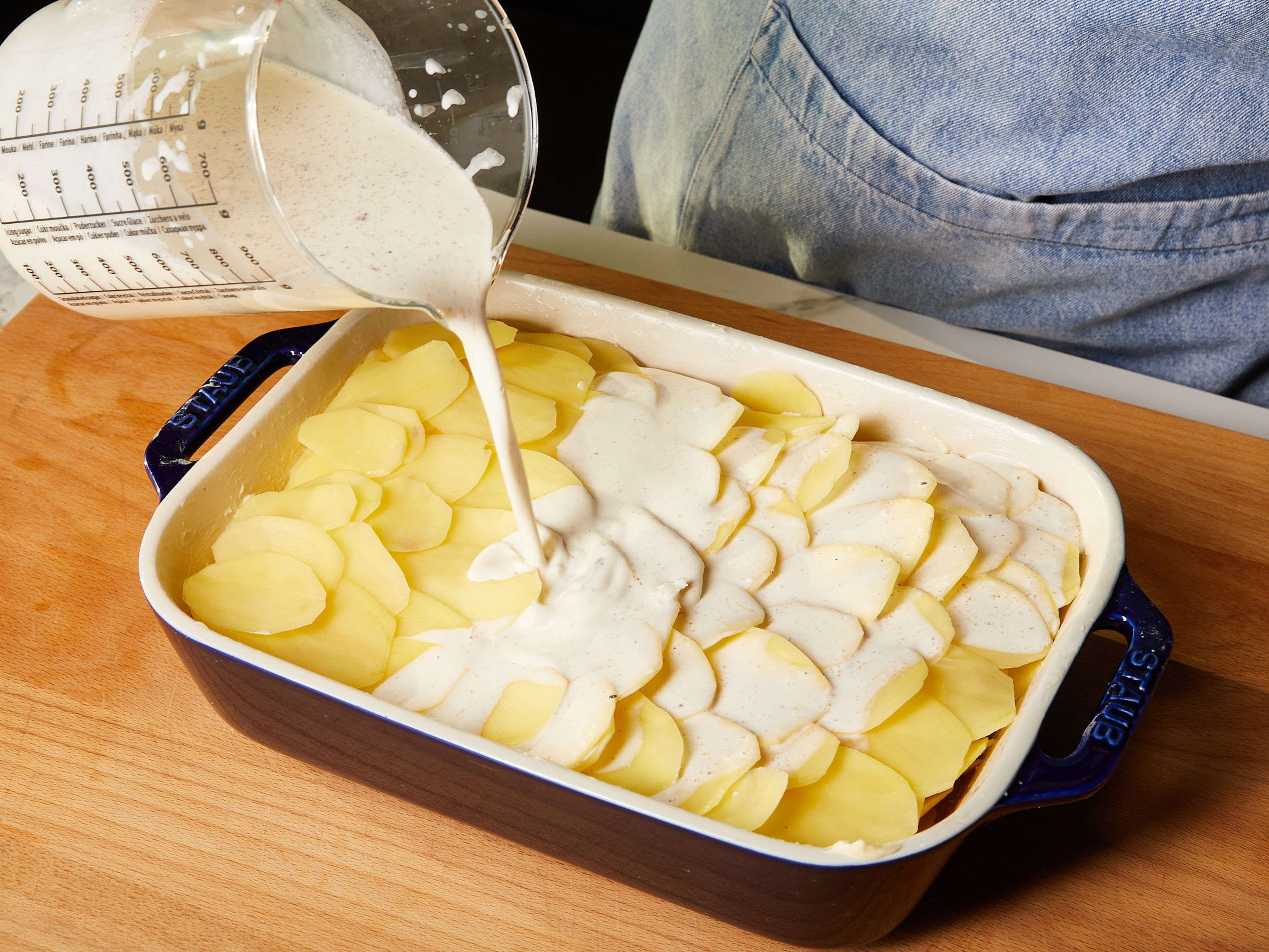 Den verbliebenen Knoblauch in eine Schüssel reiben. Sahne hinzugeben und mit Muskatnuss, Salz und Pfeffer abschmecken. Die Sahne gleichmäßig über die Kartoffeln gießen. Im vorgeheizten Backofen auf mittlerer Schiene ca. 45—50 Min. goldbraun backen. Vor dem Servieren ca. 5 Min. abkühlen lassen.