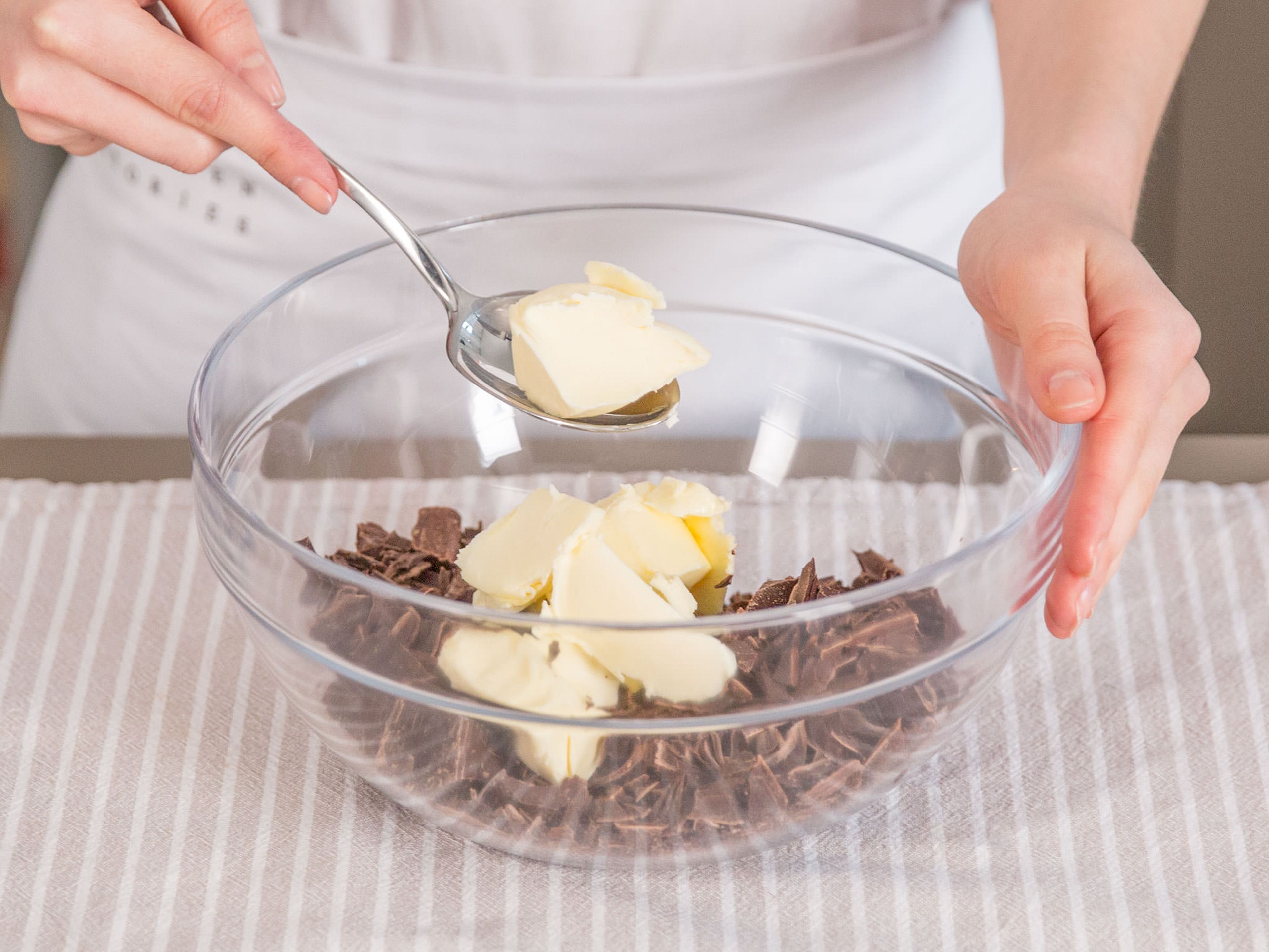 Backofen auf 180°C vorheizen. Kuvertüre grob hacken. Butter würfeln. Anschließend beides mit Zucker in der Mikrowelle bei 600 Watt für ca. 2 – 3 Min. schmelzen lassen.