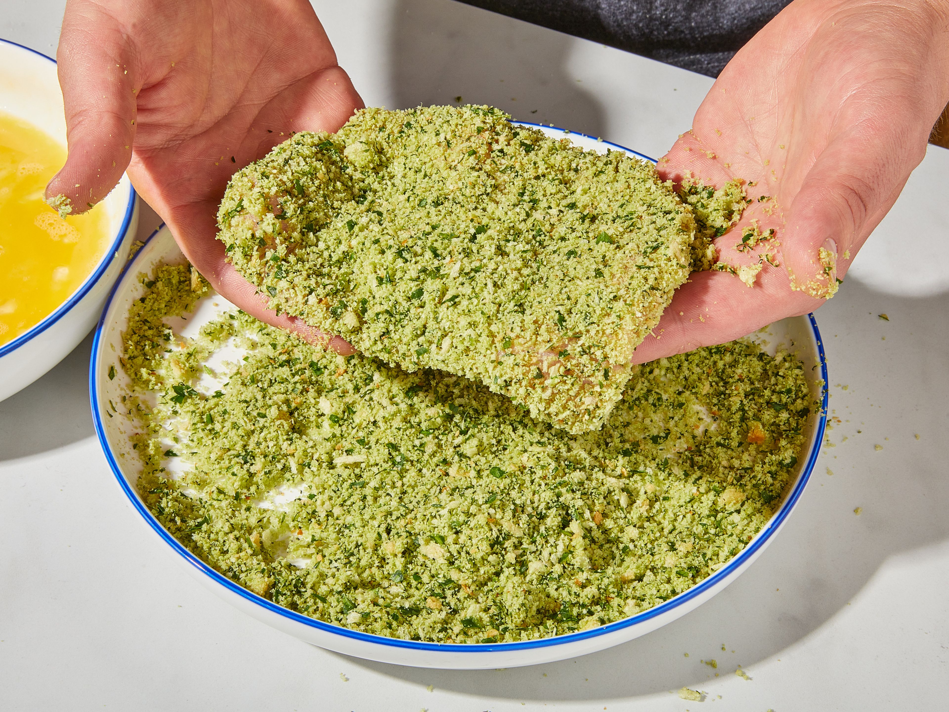 Die Schweineschnitzel mit etwas Zitronensaft beträufeln und mit Salz würzen. Kräuter, etwas Salz und das Toastbrot in einen Mixer geben und fein zerkleinern. Die Kräuterpanade in eine flache Schüssel geben. Eier in einer weiteren flachen Schüssel verquirlen. Mehl in eine dritte flache Schüssel geben. Jedes Schnitzel zuerst in Mehl, dann in Ei und schließlich in der Kräuterpanade wenden.