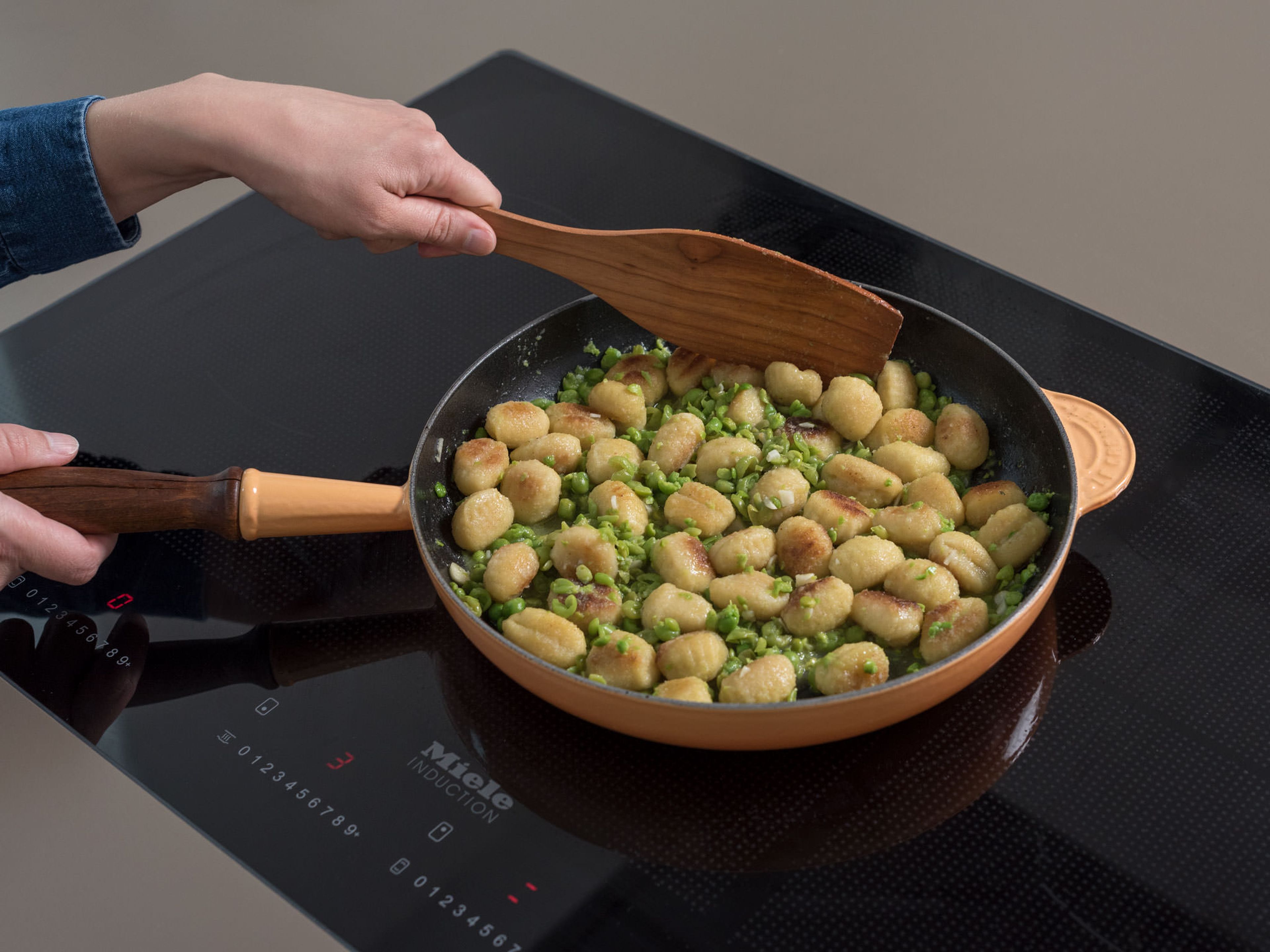 Gehackten Knoblauch zu den Gnocchi geben und ca. 2 Min. anbraten. Geflügelfond und die gestampften Erbsen dazugeben und vermengen. Ca. 3 Min. köcheln lassen.