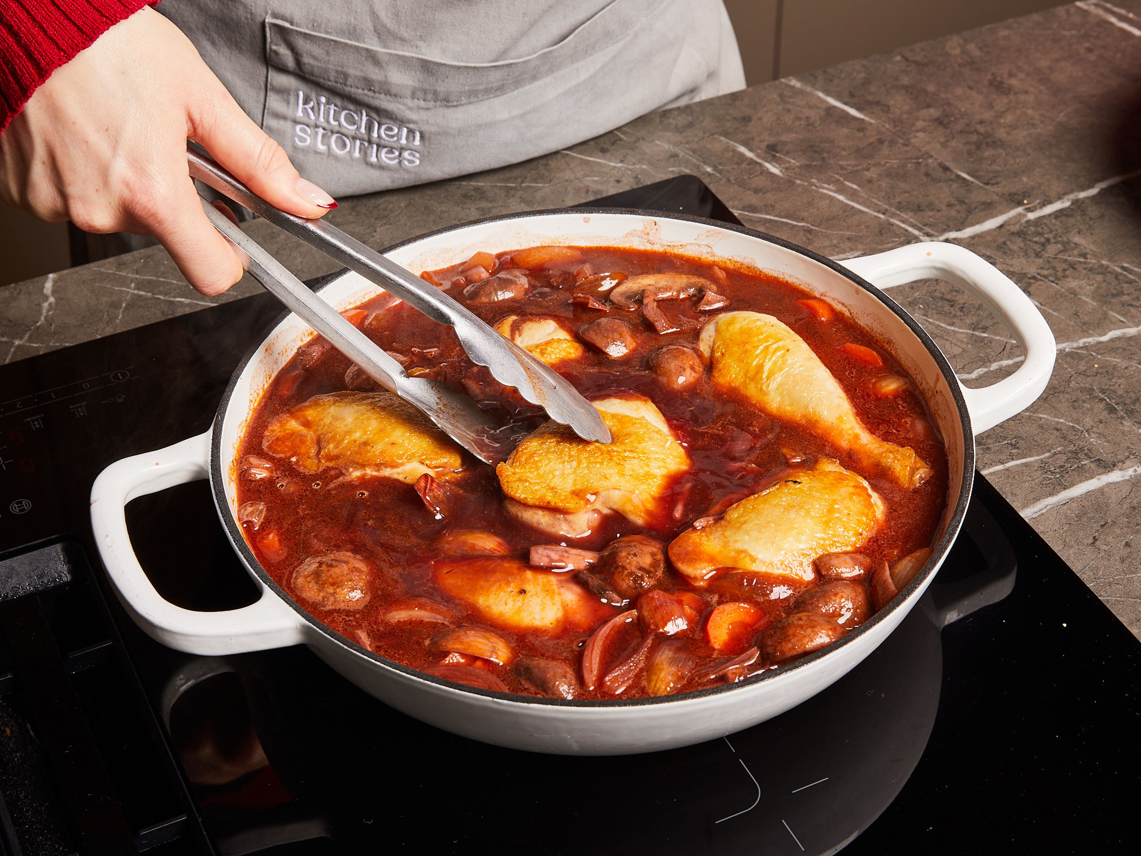 Mit dem restlichen Rotwein und der Hühnerbrühe aufgießen. Das Hähnchenfleisch, Lorbeerblatt, Thymian- und Rosmarinzweige hinzufügen und bei mittlerer Hitze und geschlossenem Deckel ca. 30 Min. köcheln lassen.