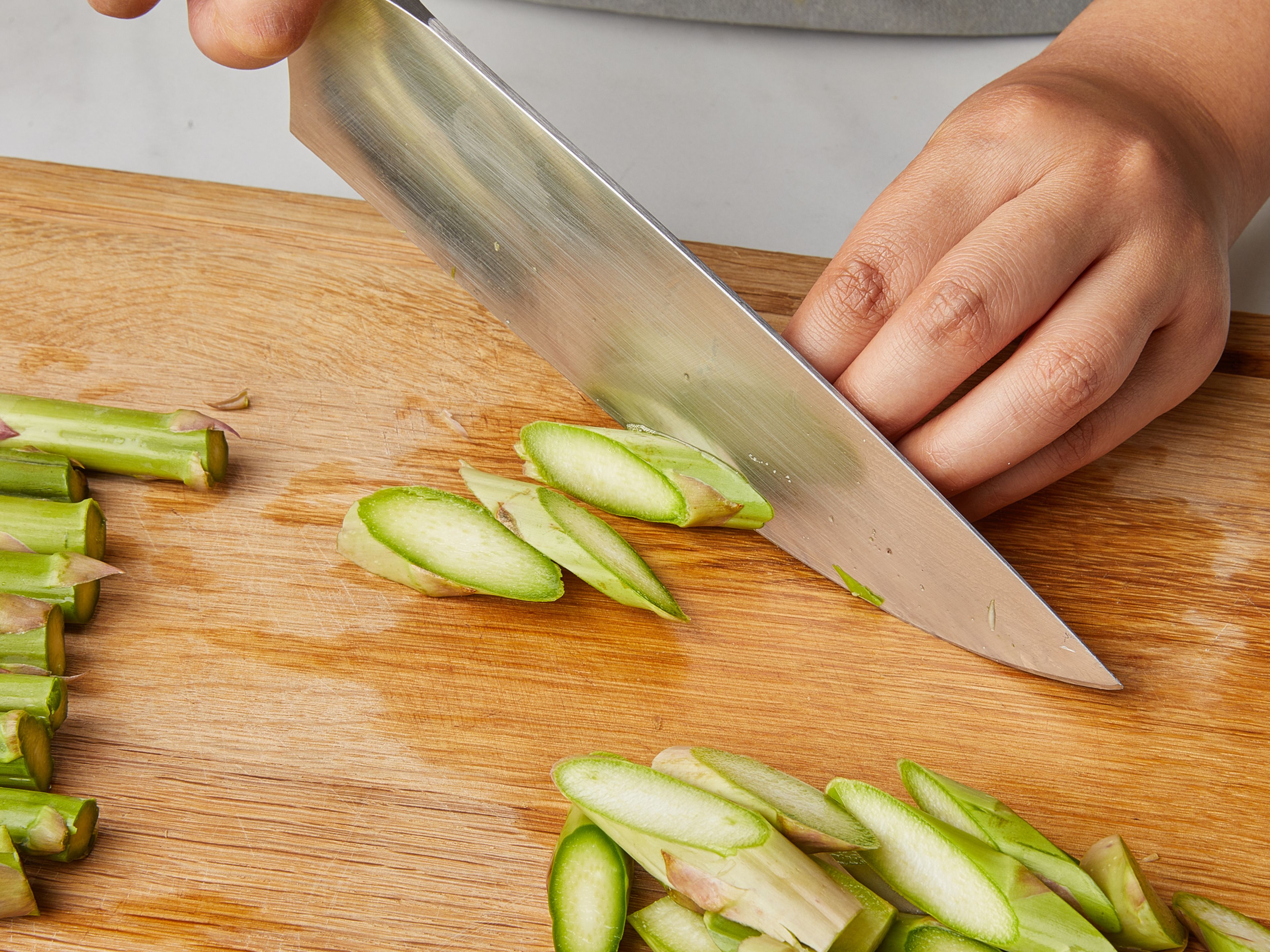 Remove the woody ends from the asparagus and cut diagonally into about 2cm / 0.8 inch pieces. Finely slice the garlic. Peel the lemon and separate the segments. In doing so, collect any juices that come out. Then roughly chop the basil and set aside. Bring a large pot of water to a boil and add salt.