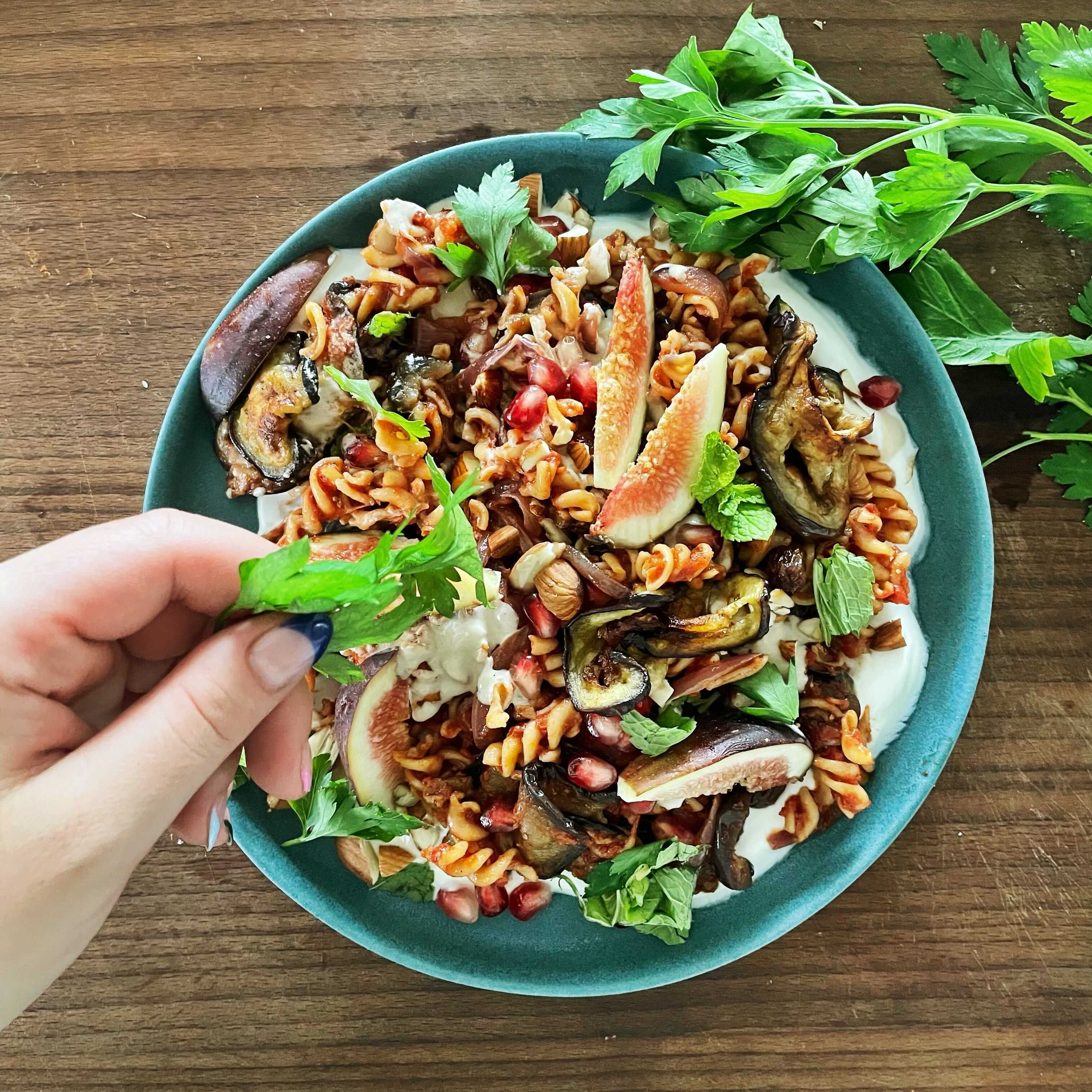 Mix the tahini with a little pasta water until creamy. Then drain the pasta and mix with some olive oil. Next, mix the pasta with the sauce. Season with salt, pepper and lemon juice. Then spread the figs, pomegranate seeds, yogurt, tahini sauce, almonds and the herbs on top. Enjoy!