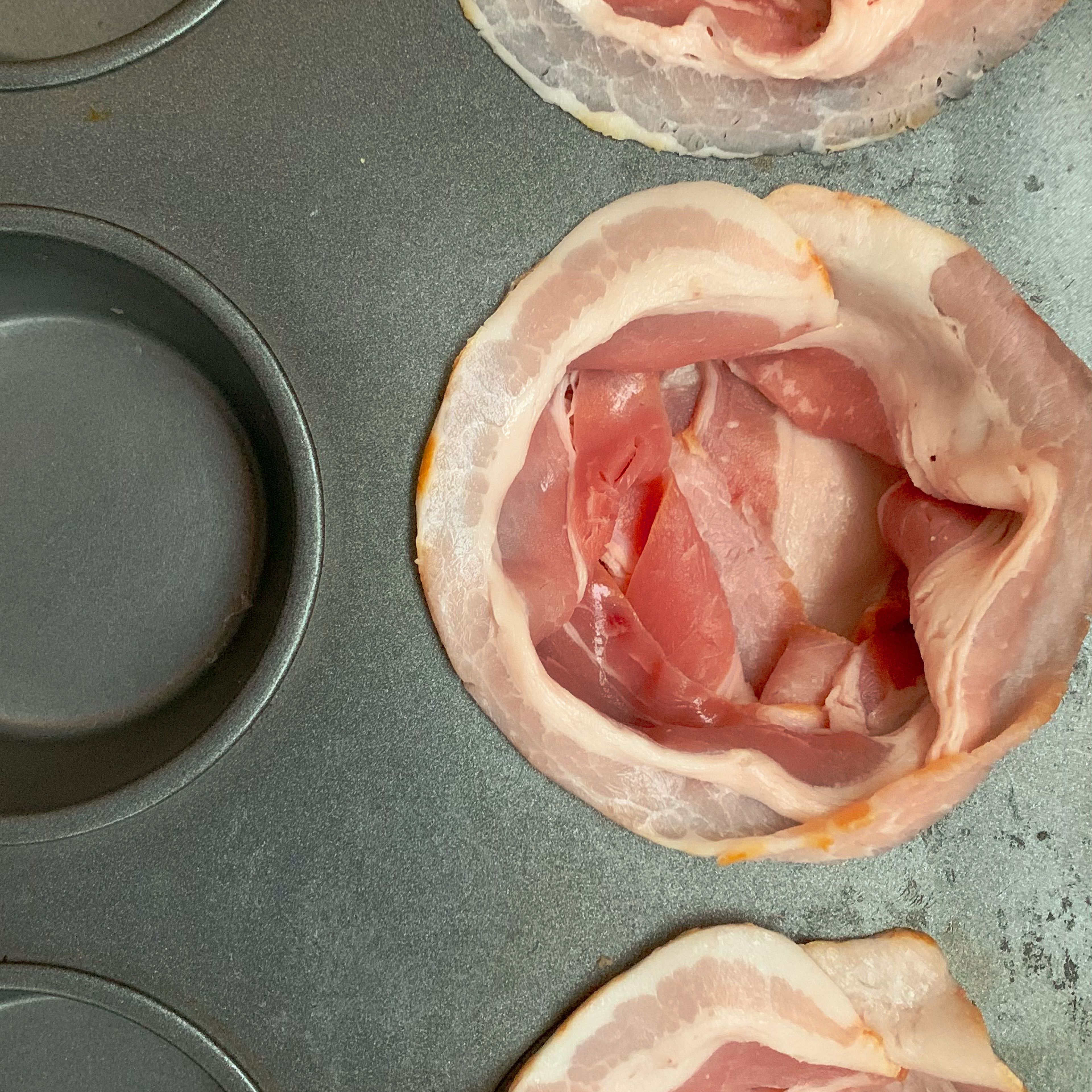 Start by setting the oven to 175 - 180 degrees Celsius or 345 - 355 Fahrenheit. You don't need to grease your muffin pan as there will be plenty of bacon fat melting away right from the start. Pad and line 4 pan wholes nicely with 4 slices of bacon each.