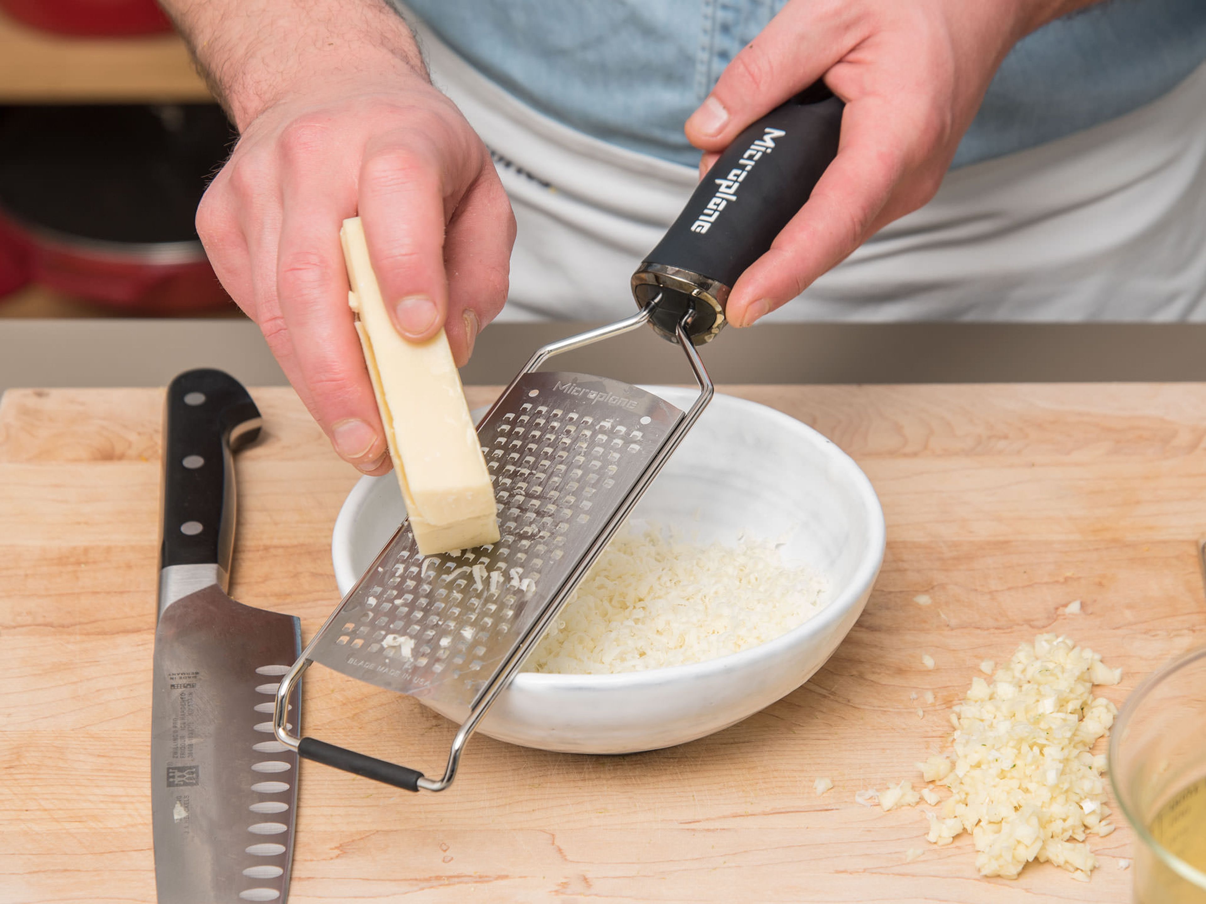 Petersilie fein hacken. Zitrone reiben und mit der Petersilie in einer kleinen Schüssel vermengen. Beiseitestellen. Knoblauch schälen und fein hacken. Greyerzer reiben und beiseitestellen. Zwiebeln schälen und in Scheiben schneiden.