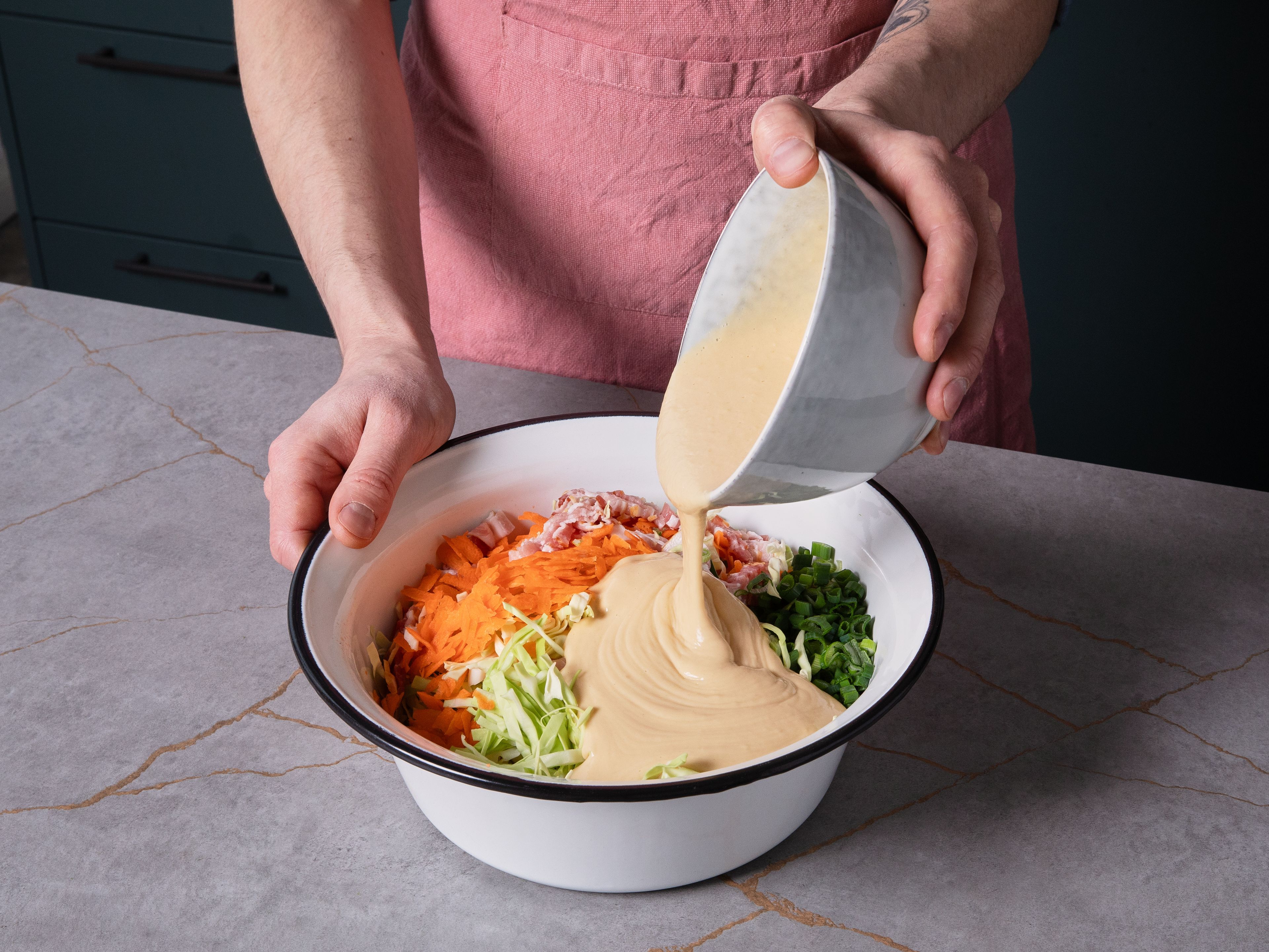 Fold sliced cabbage, grated carrots, and scallions into the batter until well combined. Add bacon pieces and mix evenly.