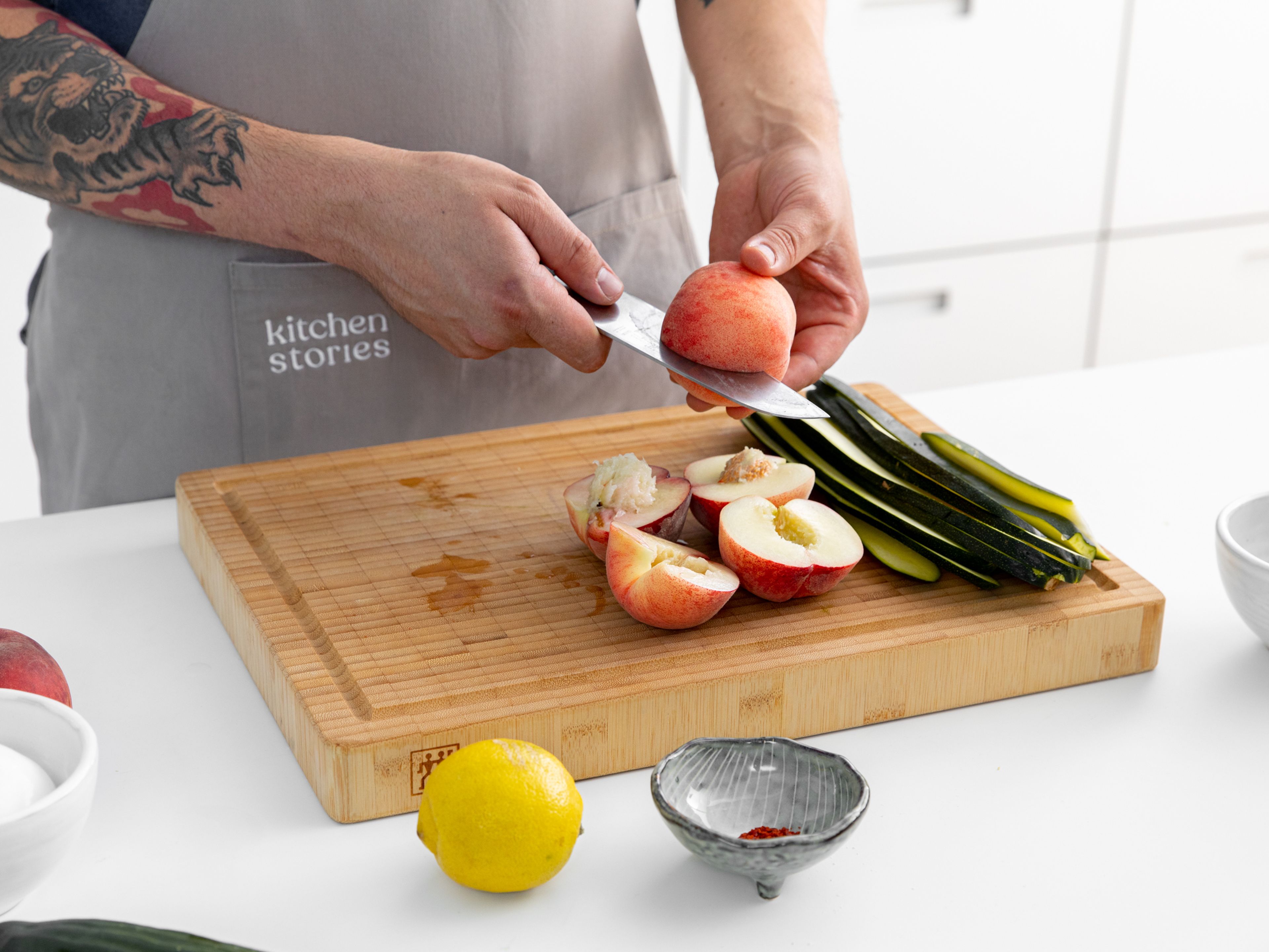 Trim the top and bottom off the zucchini and cut it lengthwise into thin strips. Halve the peaches and remove the pit. Trim the top and bottom off the cucumber, halve, remove the seeds with a spoon, then cut into thin slices.