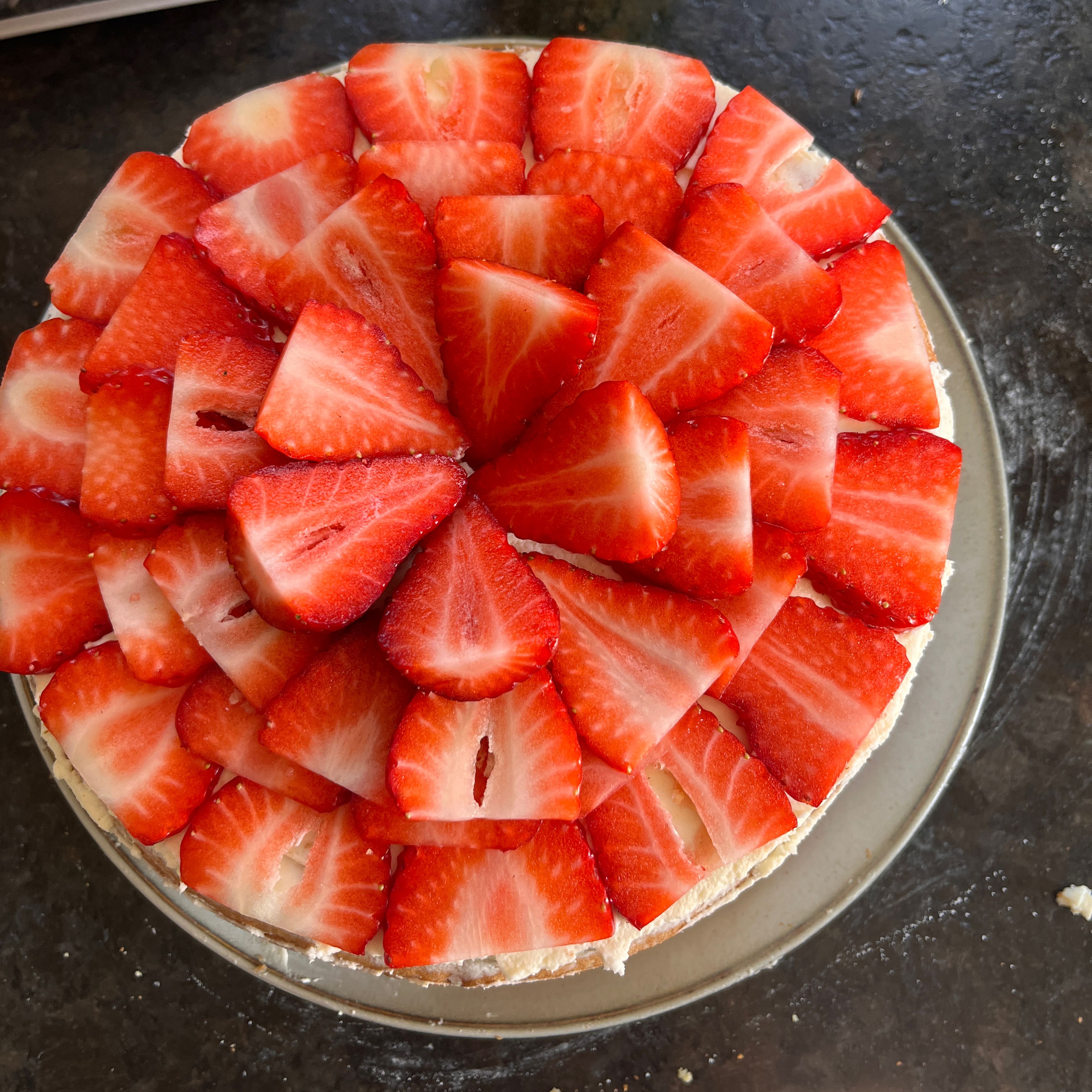 Anschließend die frischen Erdbeeren in dünne Scheiben schneiden und auf den Kuchen geben.