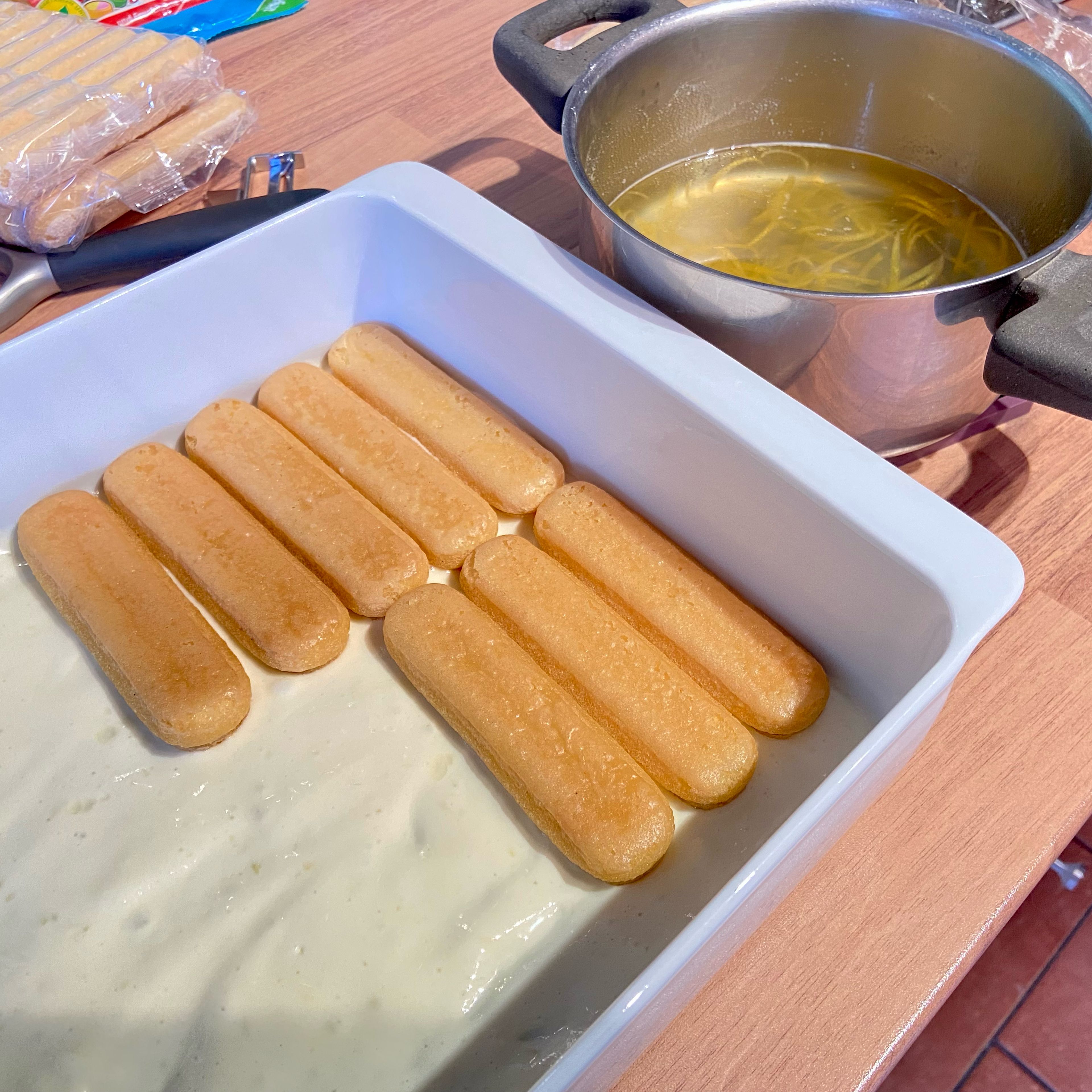 Den fertigen Eischnee zur Mascarponecreme geben und behutsam unterheben. Zuerst etwas von der Creme in die Auflaufform geben und verteilen. Die Löffelbiscuits in den abgekühlten Sirup tauchen und nebeneinander auf die Creme legen. Mit Limoncello übertröpfeln und den Vorgang wiederholen, bis die Auflaufform gut gefüllt ist. Zum Schluss vorsichtig schütteln, damit die Luft entweichen kann. Mindestens 4 Stunden im Kühlschrank ruhen lassen, am besten über Nacht.